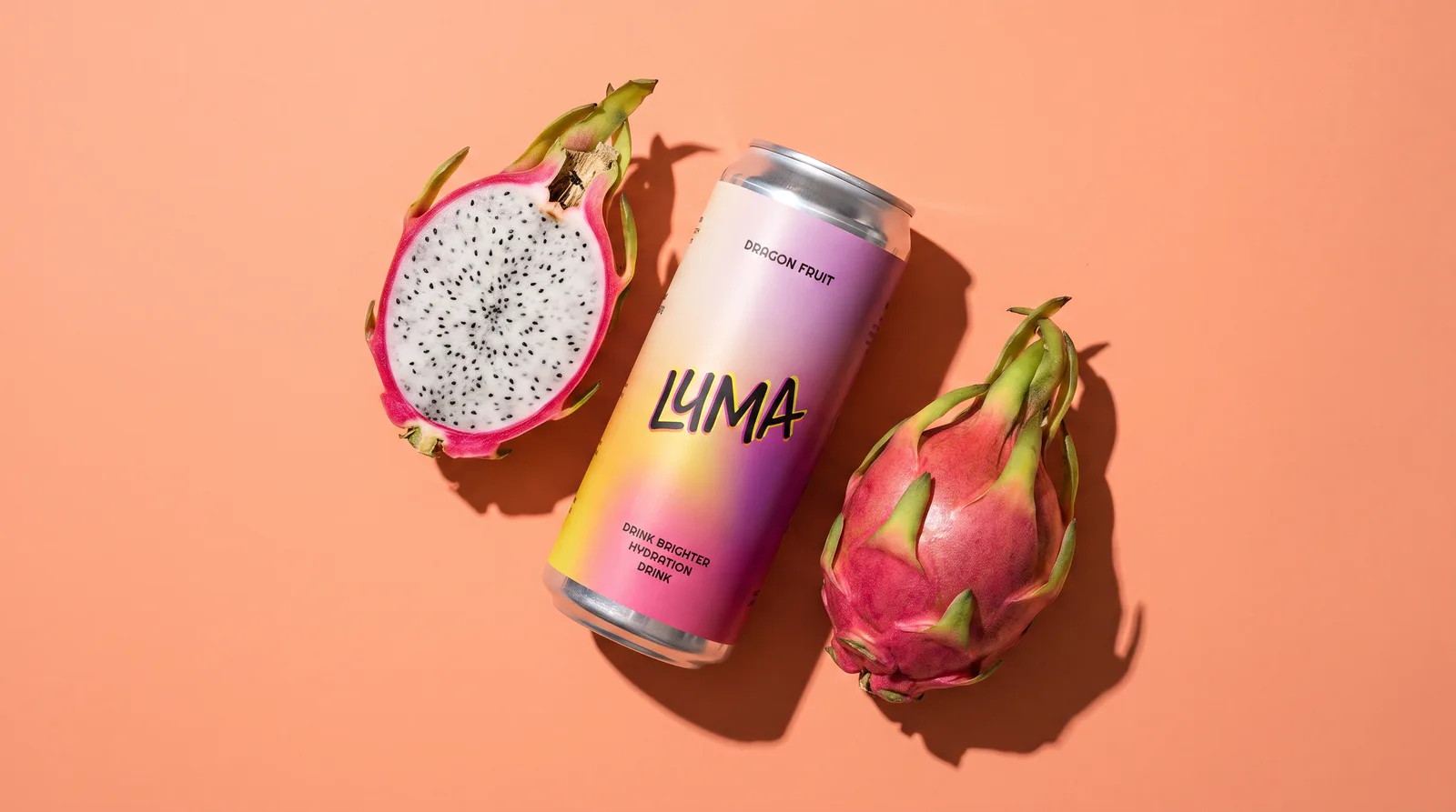 A Luma can leaning against a whole dragon fruit with a halved one beside it